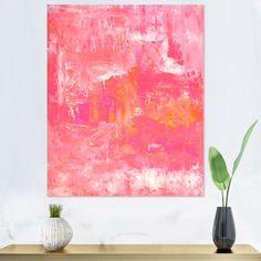 an abstract painting in pink and orange on a white wall above a wooden table with two vases