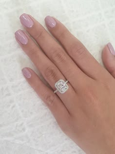 a woman's hand with pink manicured nails and a diamond ring on it