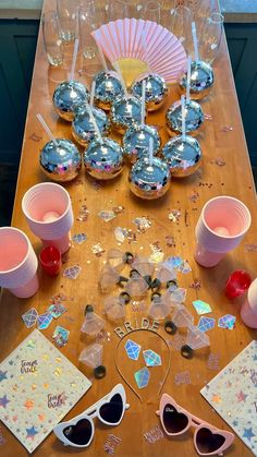 a wooden table topped with lots of glasses and confetti covered items on top of it