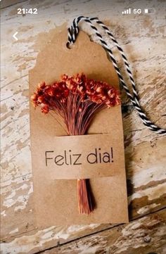 a tag that says feliz dia on it with flowers attached to it