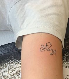 a woman's arm with the word sing tattooed on her left side ribcage