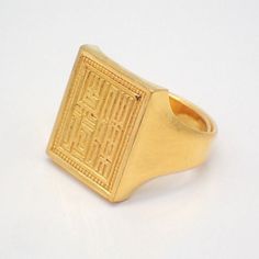 a gold signet ring with chinese writing on the front and sides, set against a white background