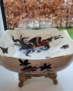 a decorative bowl sitting on top of a wooden stand in front of a glass window