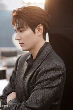 a young man with his arms crossed sitting at a desk looking off into the distance