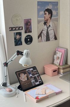 a desk with a laptop, lamp and pictures on the wall