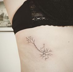 a woman's stomach with a small branch tattoo on her lower side ribcage