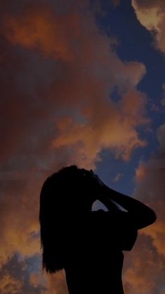 a woman is silhouetted against the sky with her hand on her head