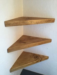 three wooden shelves in the corner of a room