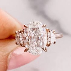 a woman's hand holding an oval diamond ring