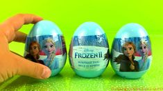 someone is holding an egg in front of three frozen princess eggs on a green surface