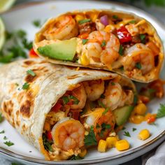 two shrimp burritos on a plate with corn, avocado and cilantro