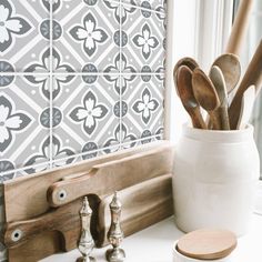 utensils and spoons are sitting in a white vase on a window sill