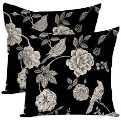 two black pillows with white flowers and birds on them, one has a bird perched on the branch