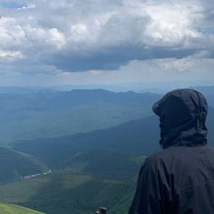 a person standing on top of a mountain looking at the sky and mountains in the distance