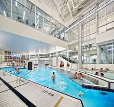 an indoor swimming pool with people in it and stairs leading up to the upper floor