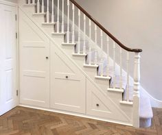 an empty room with white stairs and wooden flooring on the side of the wall