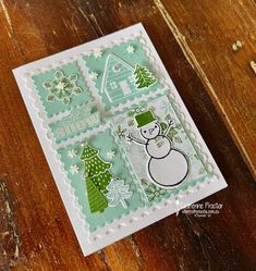 a close up of a card on a wooden table with a snowman and christmas trees