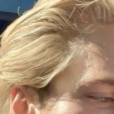 a close up of a person with blonde hair and an earring in the sun