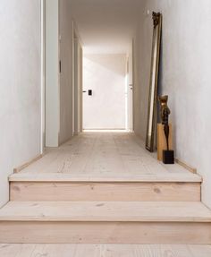 a hallway with white walls and wooden steps