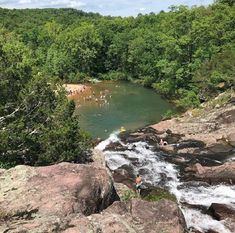 people are swimming in the river near some rocks