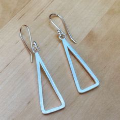 Solid sterling eco silver earrings. The earrings have a contemporary minimalist design, made from square silver wire 1.5mm thick and shaped to a simple triangular drop shape.  The triangle shape is 33mm in height and 11mm wide at the bottom.   The earrings have a smooth shiny surface although can also be made with a matte brushed silver surface if preferred, just message me.  These drop earrings are light and easy to wear in both a formal and casual setting, and I can also make a pendant to matc Modernist Silver Earrings For Gift, Modern Triangle Metal Earrings, Sterling Silver Modernist Earrings, Modernist Sterling Silver Pierced Earrings, Modernist Sterling Silver Drop Earrings, Minimalist Contemporary, Design Geometric, Contemporary Minimalist, Triangle Earrings