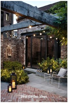 an outdoor patio with lights and plants on the outside, surrounded by brick walls and trees