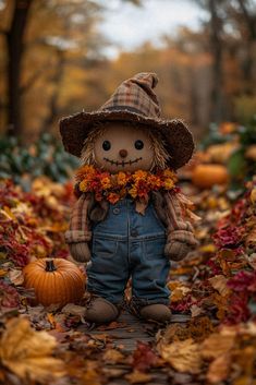 a teddy bear wearing overalls and a scarecrow hat standing in the middle of leaves