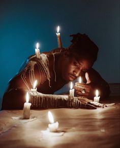 a woman leaning over a table with candles in front of her and looking at her phone