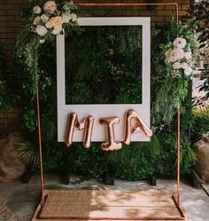 the letters are made out of copper foil and placed in front of an arch with greenery