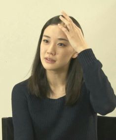 a woman sitting down with her hand on her head