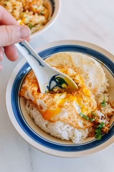 a person is spooning food out of a bowl with rice and beans on the side