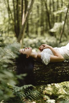 a woman laying on top of a tree in the forest