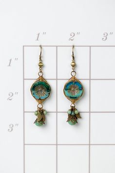 These handcrafted earrings are longer in design with a stunning Czech glass flower focal that has been hand wrapped in our signature herringbone weave with antique brass leaves and dangles of Czech glass. They are completed with antique brass ear wires and hang at approximately 2.5" in length. Antique Brass (lead and nickel free) Czech Glass 2.5", with antique brass ear wires We hand select our natural materials, thus there may be slight variations in color and/or size that will not detract from Bohemian Czech Glass Dangle Flower Earrings, Handmade Bohemian Flower Earrings With Czech Glass, Handmade Dangle Brass Flower Earrings, Handmade Brass Dangle Flower Earrings, Bohemian Wire Wrapped Flower Jewelry, Bohemian Brass Flower Jewelry, Bohemian Flower-shaped Wire Wrapped Jewelry, Artisan Czech Glass Beaded Earrings Nickel Free, Bronze Wire Wrapped Czech Glass Earrings