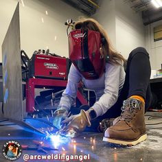 a woman welding something on the floor in a garage with sparks coming out of her shoes