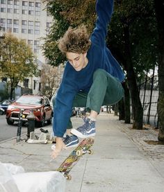 a young man is doing a trick on his skateboard in the air over a sidewalk