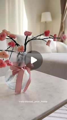 a vase with pink flowers in it sitting on a table next to a couch and lamp