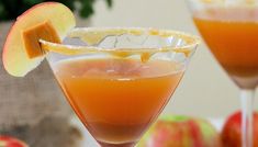 two glasses filled with orange juice and garnished with an apple slice