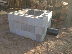 a cinder block sitting in the middle of a yard next to some trees and logs