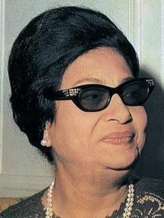 an older woman wearing black sunglasses and pearls