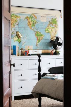 a bedroom with a map on the wall next to a bed and dresser in front of it