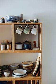 the shelves are filled with bowls and plates on them, along with other kitchen ware