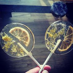 two lollipops with orange slices on them are being held by someone's hand