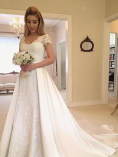 a woman in a white wedding dress holding a bouquet and looking at the camera with an open door behind her