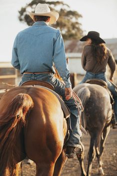 two people riding horses in the dirt