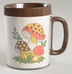 a brown and white coffee mug with mushrooms painted on the side, sitting in front of a white background