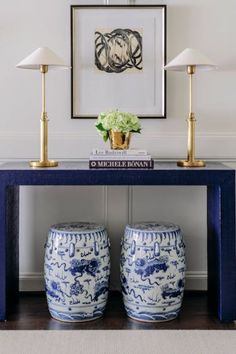 a blue and white table with two vases next to it on the sideboard