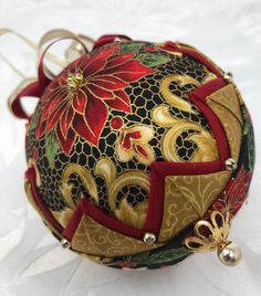 a christmas ornament with red and gold designs on it's side, sitting on a white surface