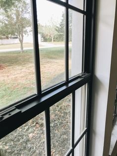 a cat sitting on the ledge of a window looking out at a grassy area outside