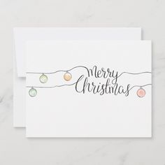 a christmas card with the words merry christmas written on it and ornaments hanging from strings