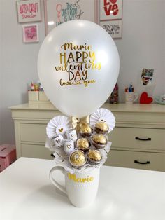 a white coffee cup filled with chocolates and a balloon that says happy valentine's day